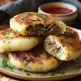 Plate of golden brown potato cakes with meat filling.