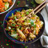 A bowl of stir-fried veggies and meat with chopsticks.