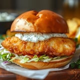 A crispy fish sandwich on a toasted bun with lettuce and tangy sauce.
