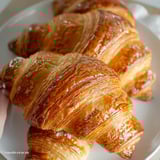 Two croissants on a plate, with one closer up and the other further back.