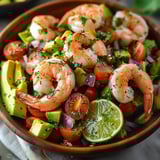 Juicy shrimp salad with avocado, lime, and veggies in a bowl.