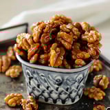 A bowl of pecans with a spoon in it.
