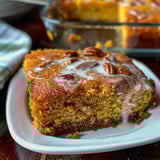 A slice of nut-topped cake sitting on a white plate.