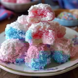 A vibrant assortment of pink, blue, and white frosting-covered cakes on a plate.
